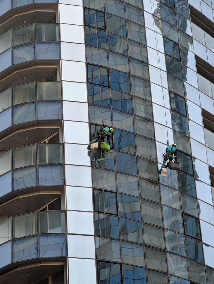 creative-01 Professional window cleaners working on a skyscraper in Abu Dhabi, showcasing urban architecture.